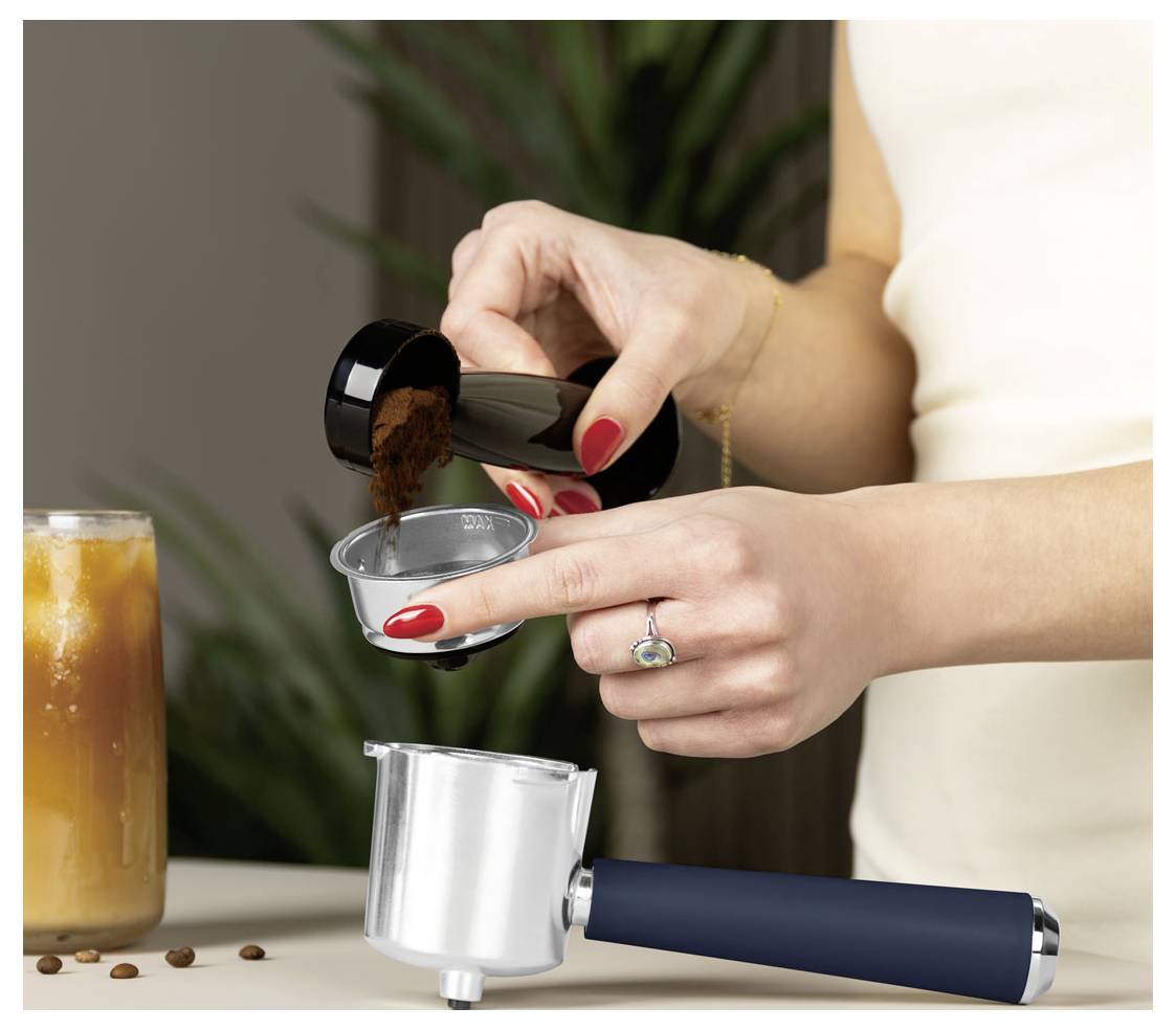 Žena plní filtr na kávu mletou kávou vedle filtru na espresso a nápoje z kávy.