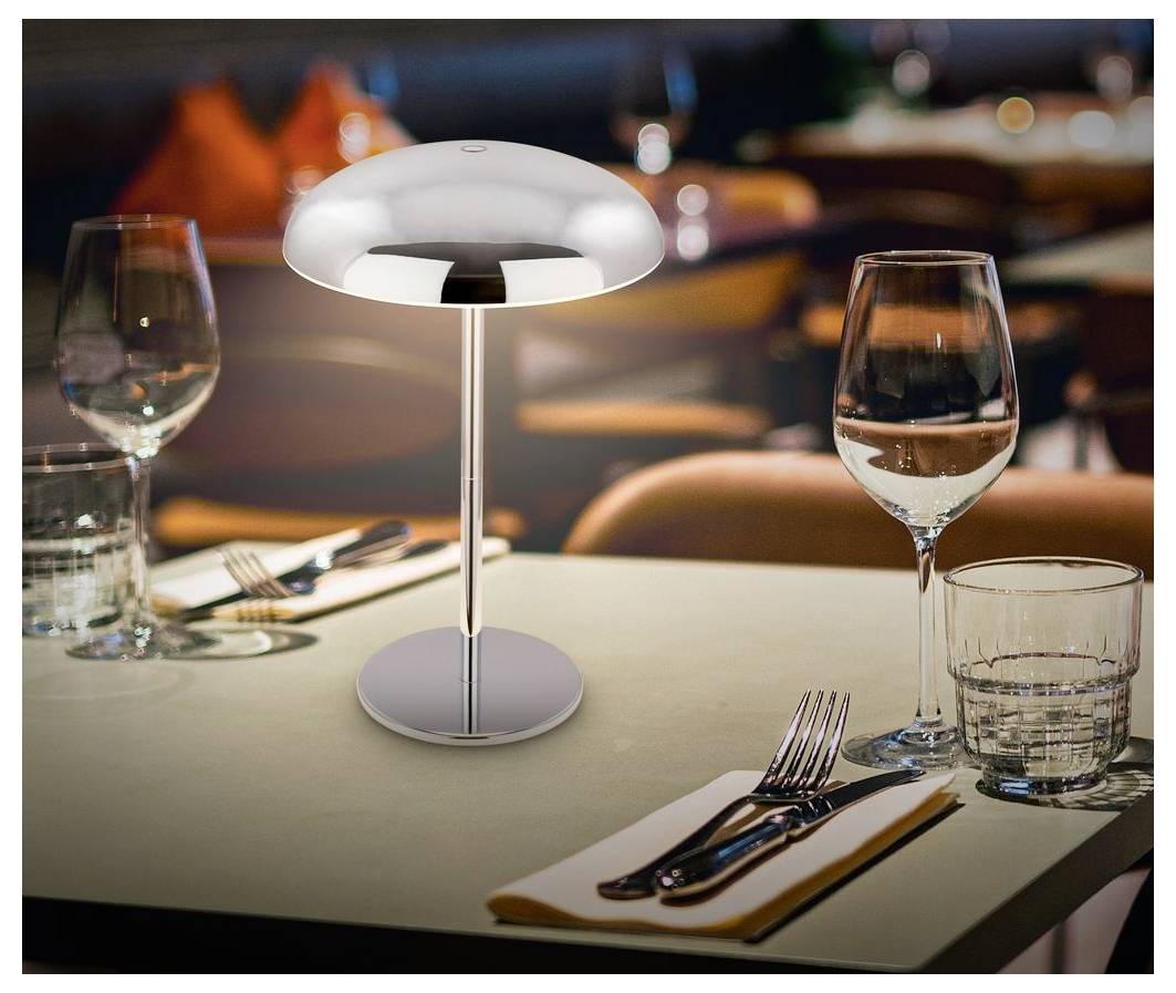 Moderní stolní lampa na restauračním stole se sklenicí na víno, sklenicí na vodu a příborem v jemně osvětlené jídelně.