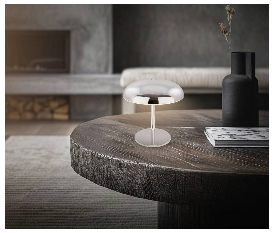 Malá moderní stolní lampa tvaru houby zářící na kulatém dřevěném konferenčním stole vedle černé vázy a časopisu v minimalistickém obývacím pokoji.