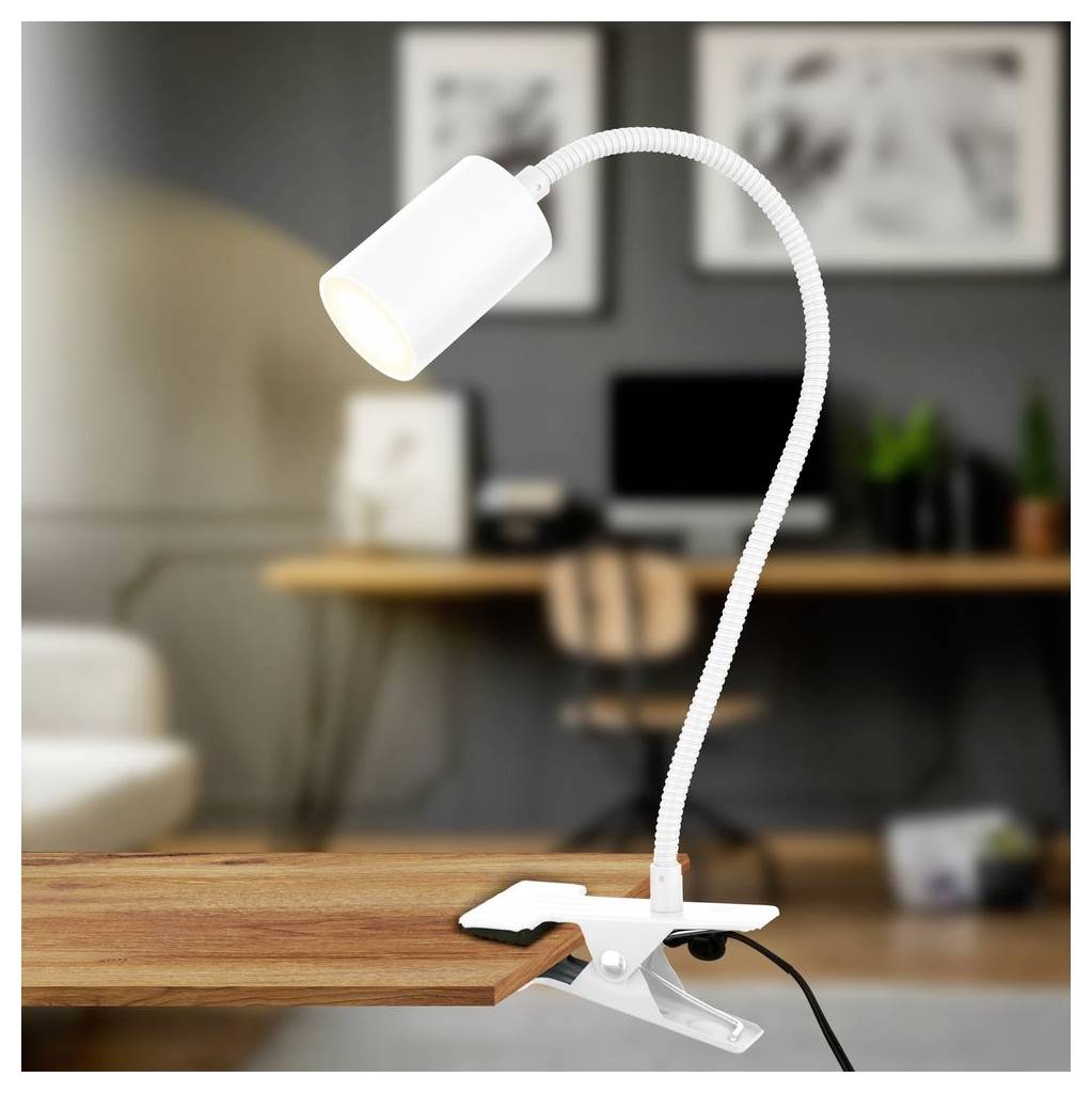 Bílá upínací stolní lampa s ohebným krkem, upnutá na dřevěný stůl v rozmazaném prostředí domácího kanceláře.