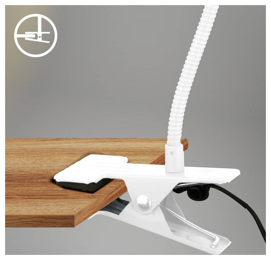 Bílá stolní klipová lampa připevněná na okraj dřevěného stolu s viditelným ohebným článkovitým krkem a elektrickým kabelem.