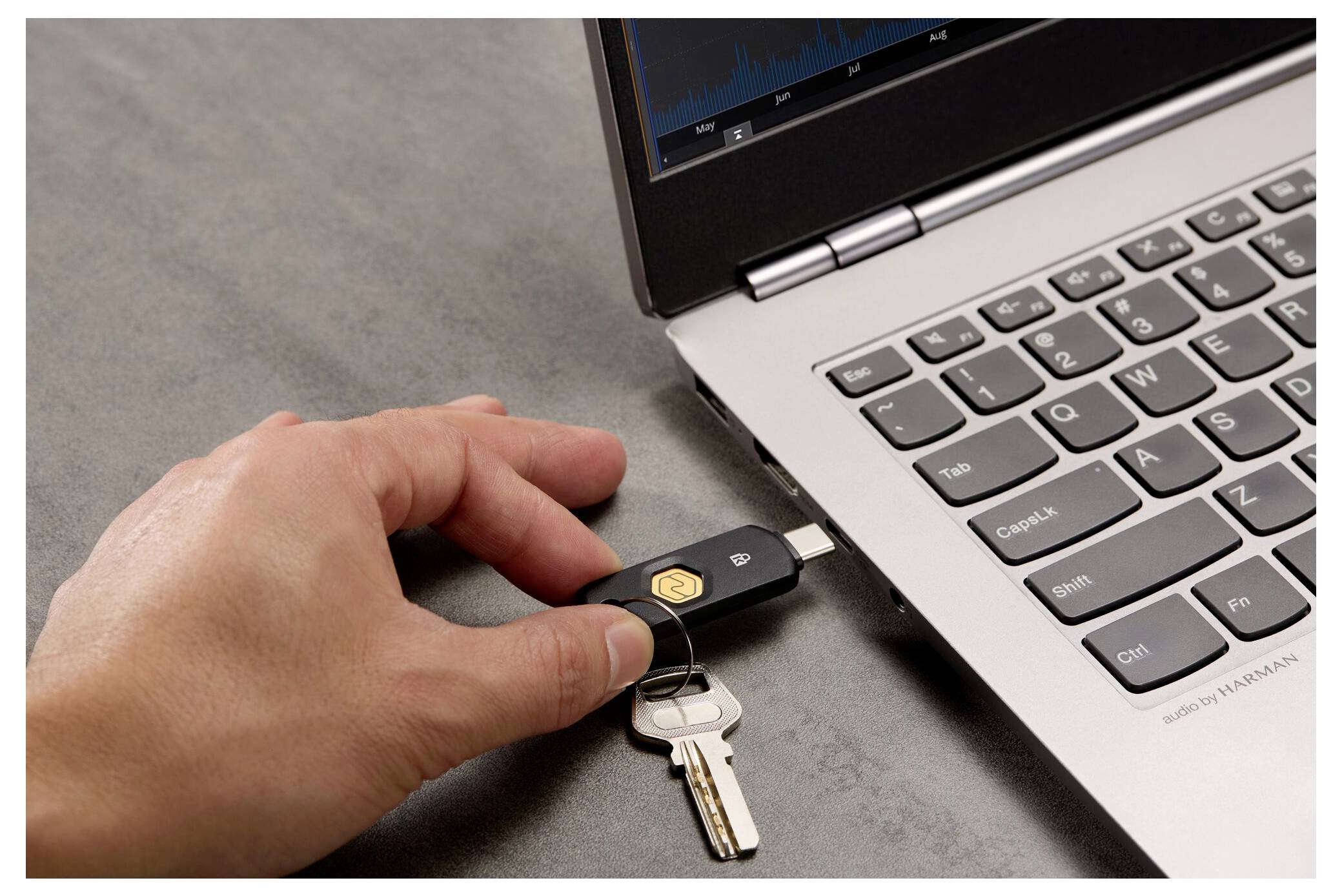 Muž zapojuje USB bezpečnostní klíč do notebooku, poblíž jsou dva klíče na klíčence.