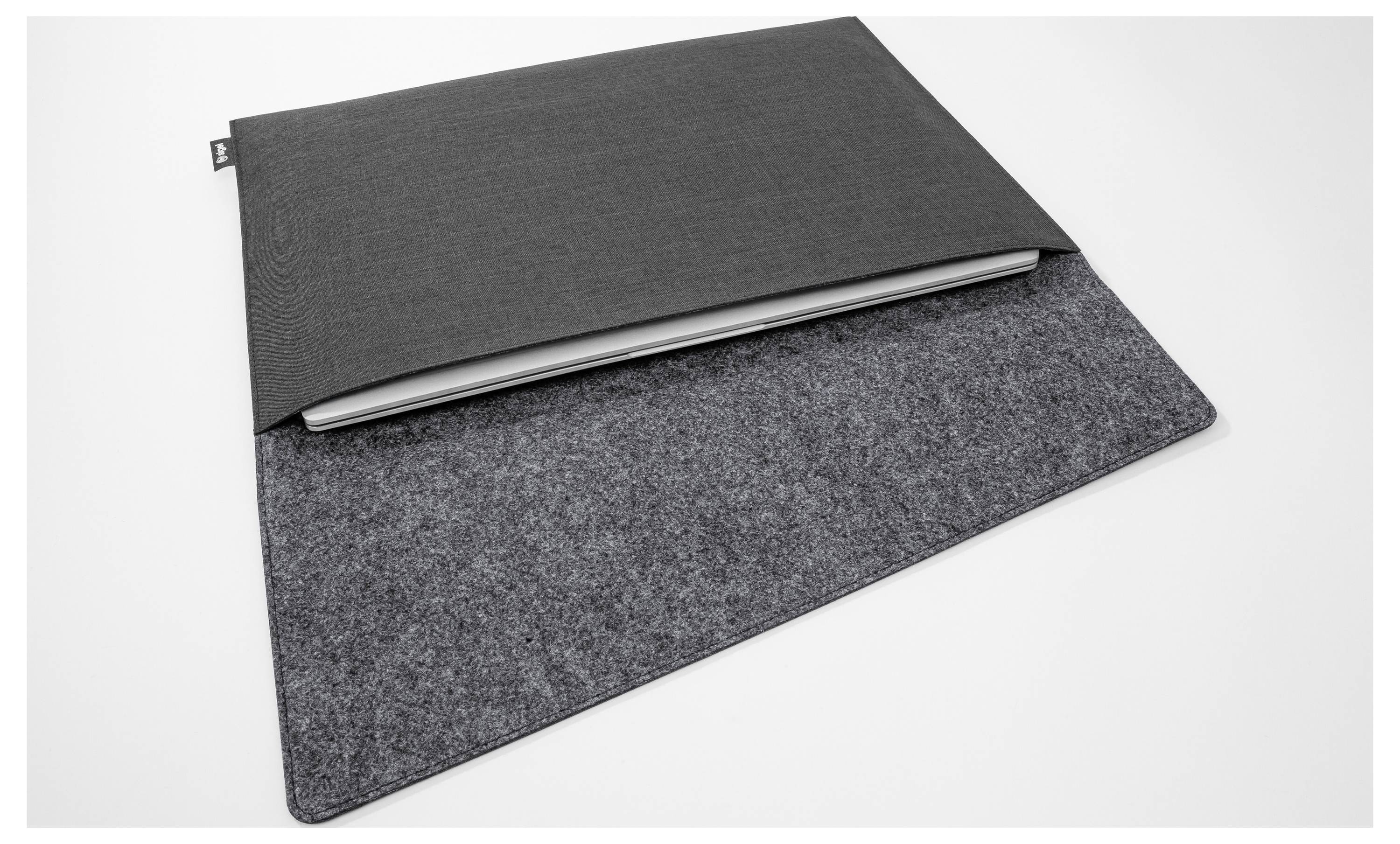 Dva šedé filcové pouzdra na notebook naskládaná na bílém pozadí, jedno tmavší a jedno světlejší, částečně otevřená, aby bylo vidět notebook uvnitř.