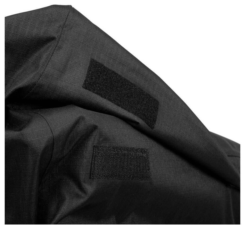 Detailní snímek černé látky se dvěma přišitými pásky suchého zipu na texturovaném oděvu nebo tašce.