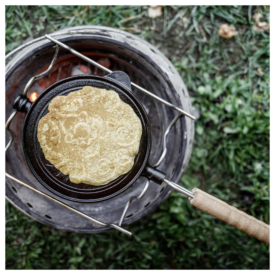 Tortilla nebo placka se vaří v pánvi nad venkovním uhlím topením, pohled shora.