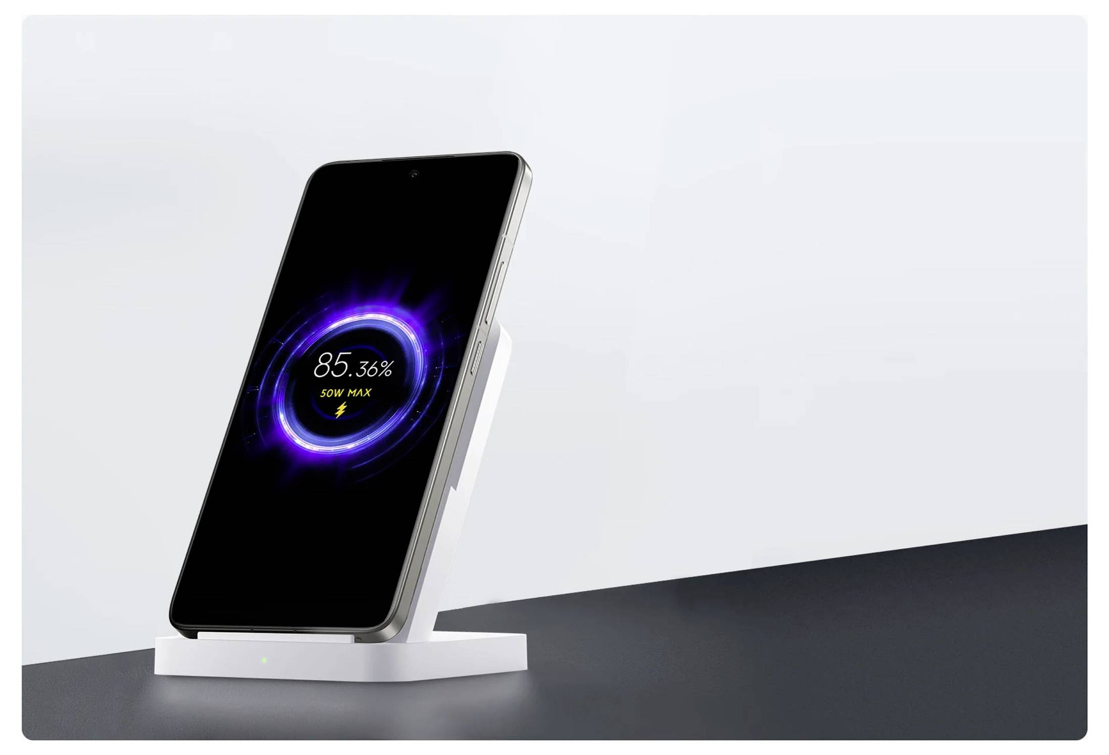 Smartphone nabíjející se na bílém bezdrátovém stojanu se obrazovkou ukazující 85,36% baterie a "50W MAX" v zářícím fialovém kruhu.