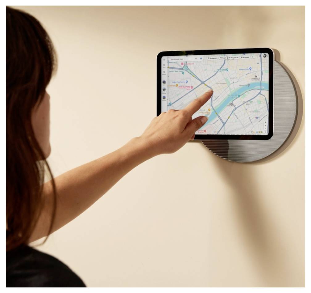 Žena se dotýká na stěně umístěné tabletu, na kterém je zobrazena aplikace navigace s mapou.