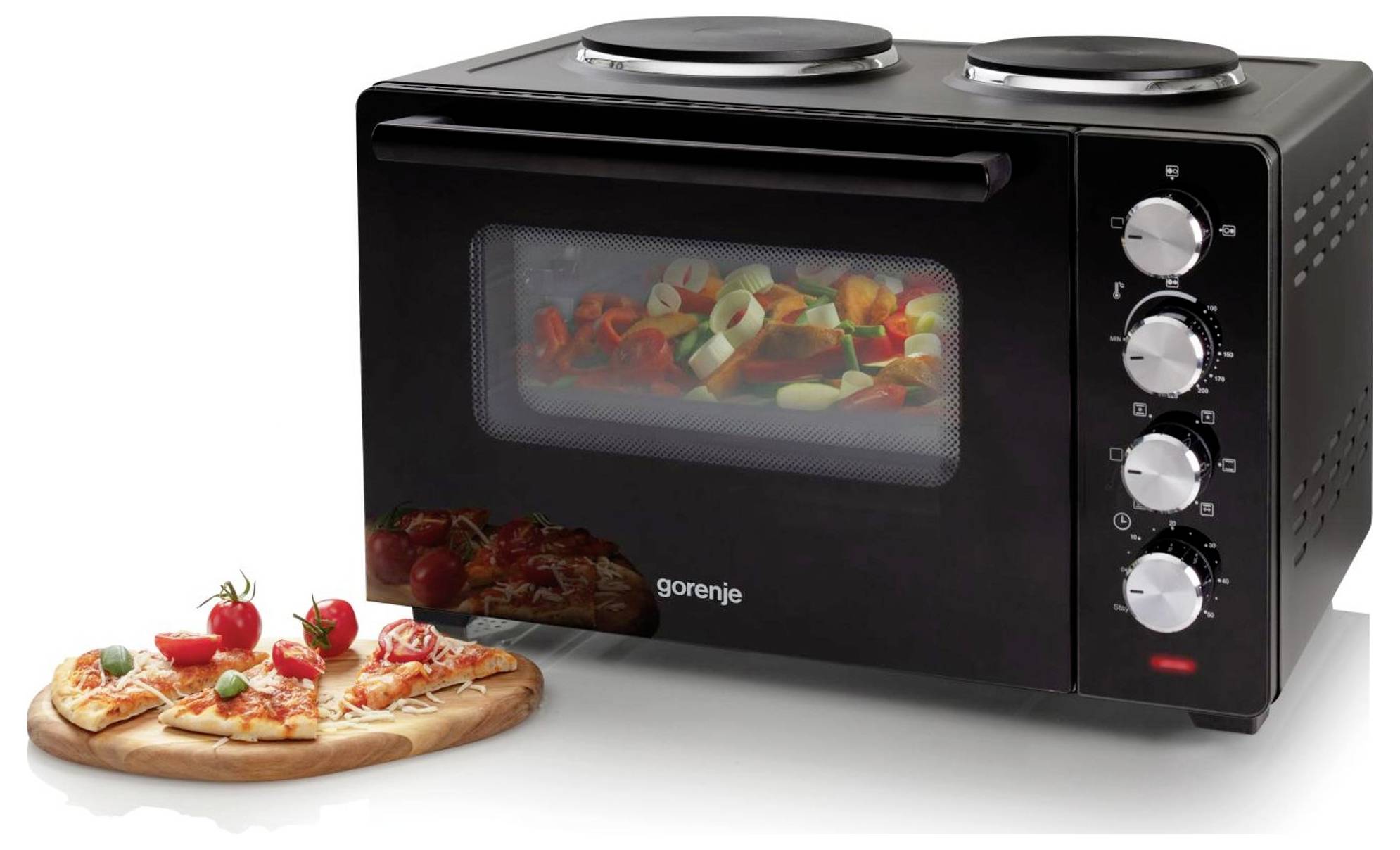 Černá kuchyňská mini trouba s pracovní deskou se dvěma hořáky nahoře, přední oknem, ovládacími kolečky a pizzou na dřevěné desce vedle ní.