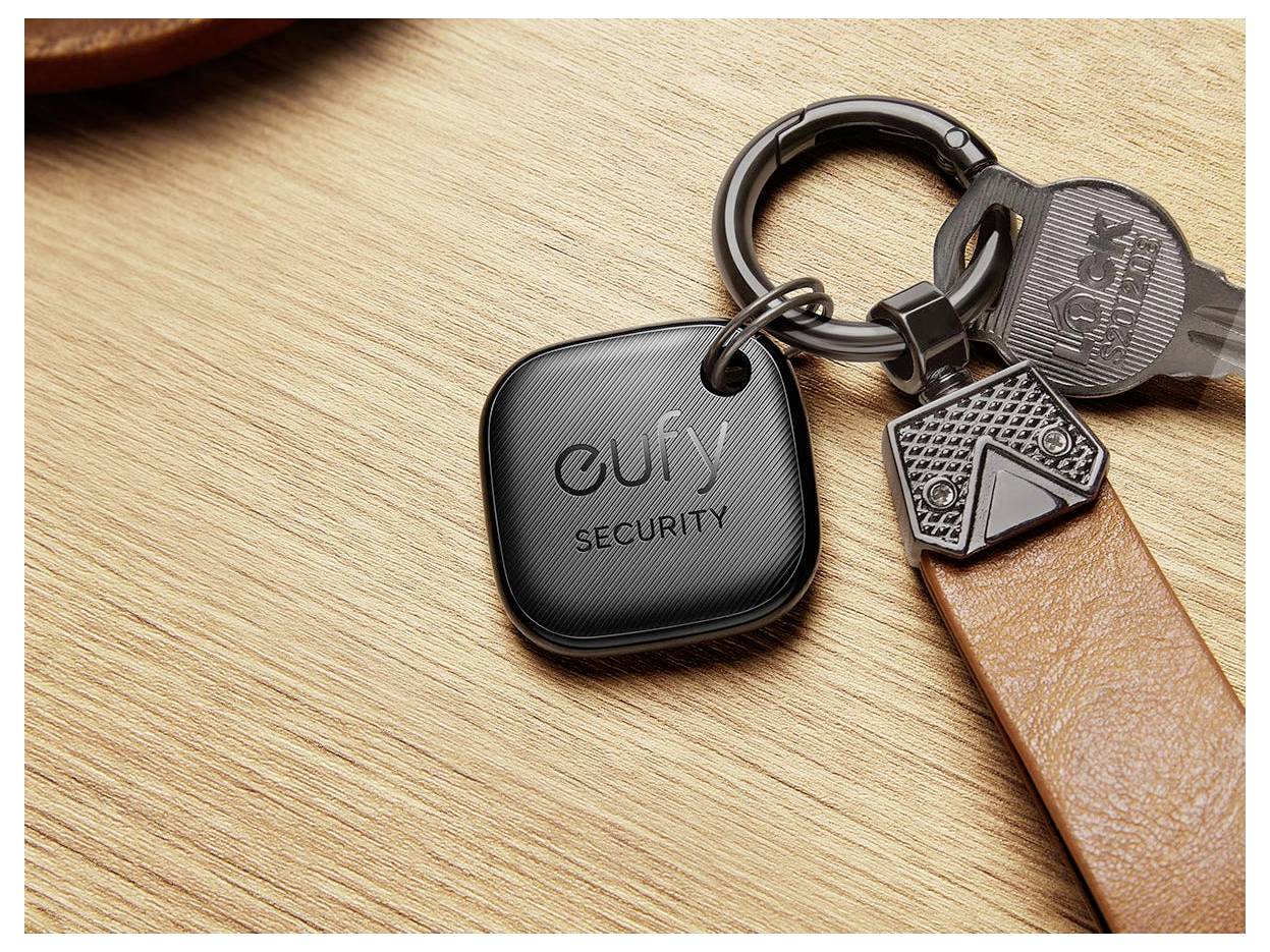 Eufy Security klíčenka přiřazená na klíčenku s klíči a hnědým koženým páskem na dřevěném povrchu.