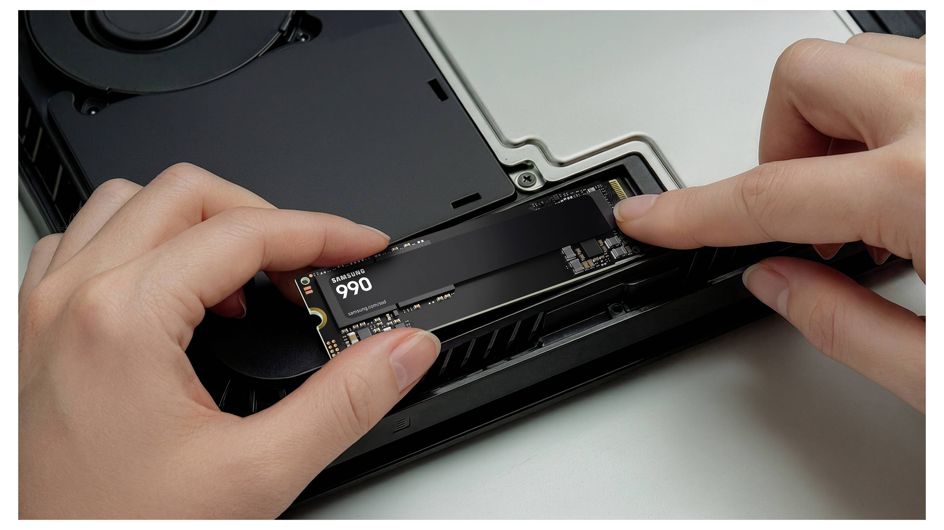 Ruce instalují M.2 SSD do počítačové základní desky uvnitř otevřené skříně.