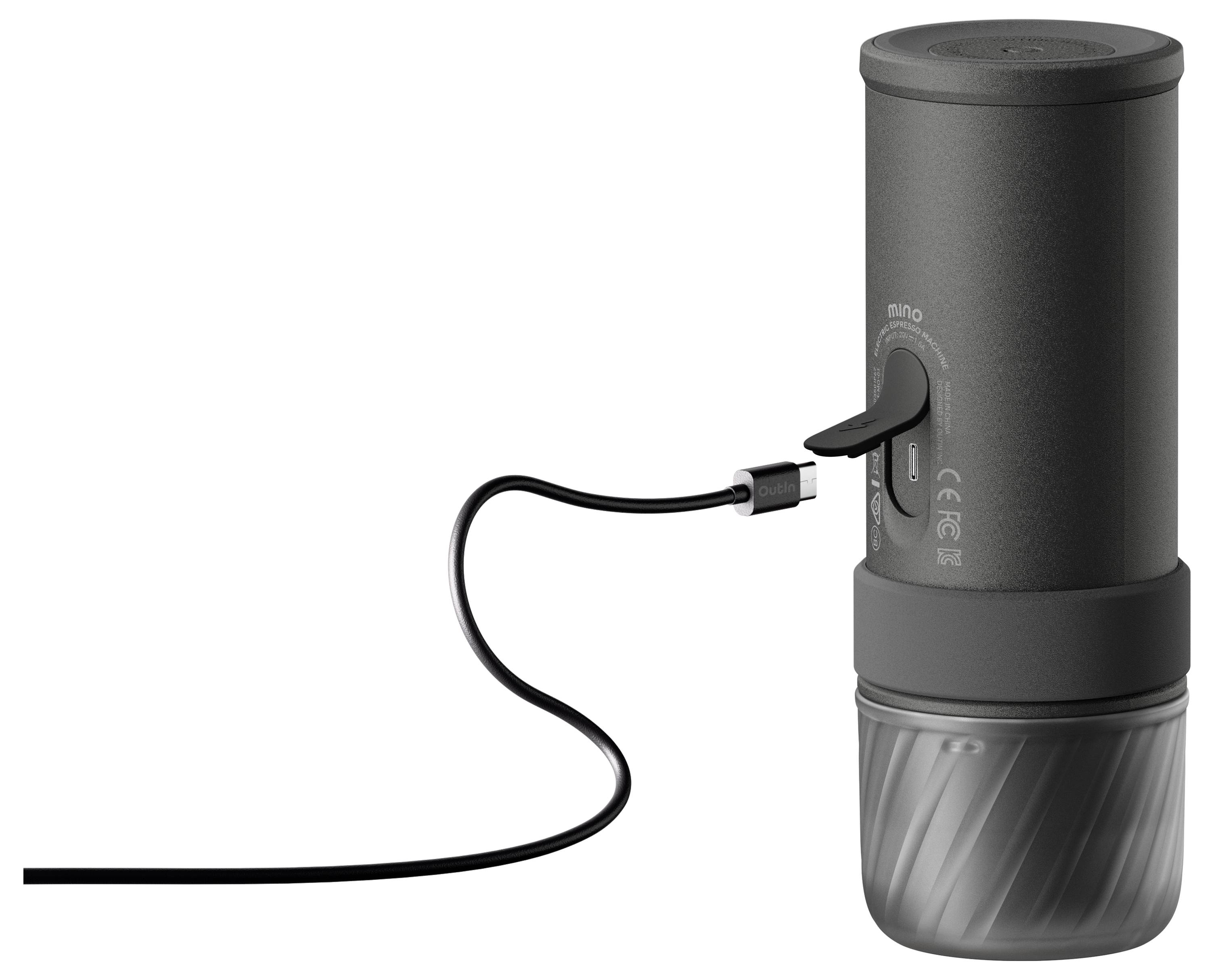 Přenosné černé válcové zařízení s USB kabelem zapojeným do jeho boku, stojící vzpřímeně na bílém pozadí.