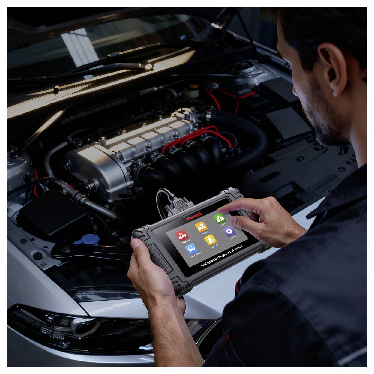 Mechanik používá přenosný diagnostický tablet k inspekci motorů automobilu s otevřenou kapotou.