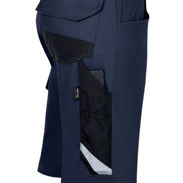 Detailní záběr na modré pracovní kalhoty se zesílenými černými bočními kapsami a reflexním lemem.