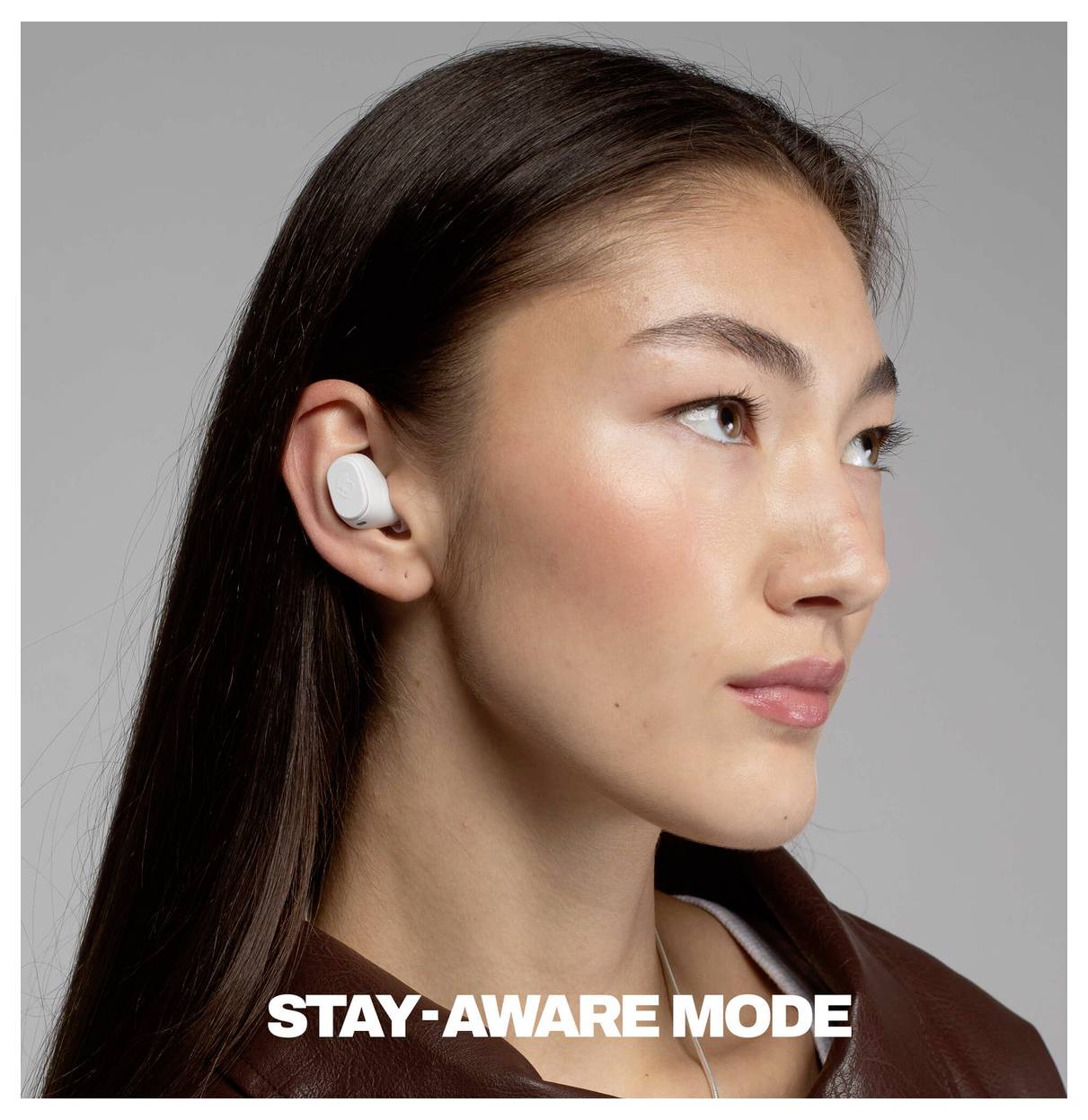 Portrét ženy s bílou bezdrátovou sluchátkou, s textem „STAY-AWARE MODE" dole.