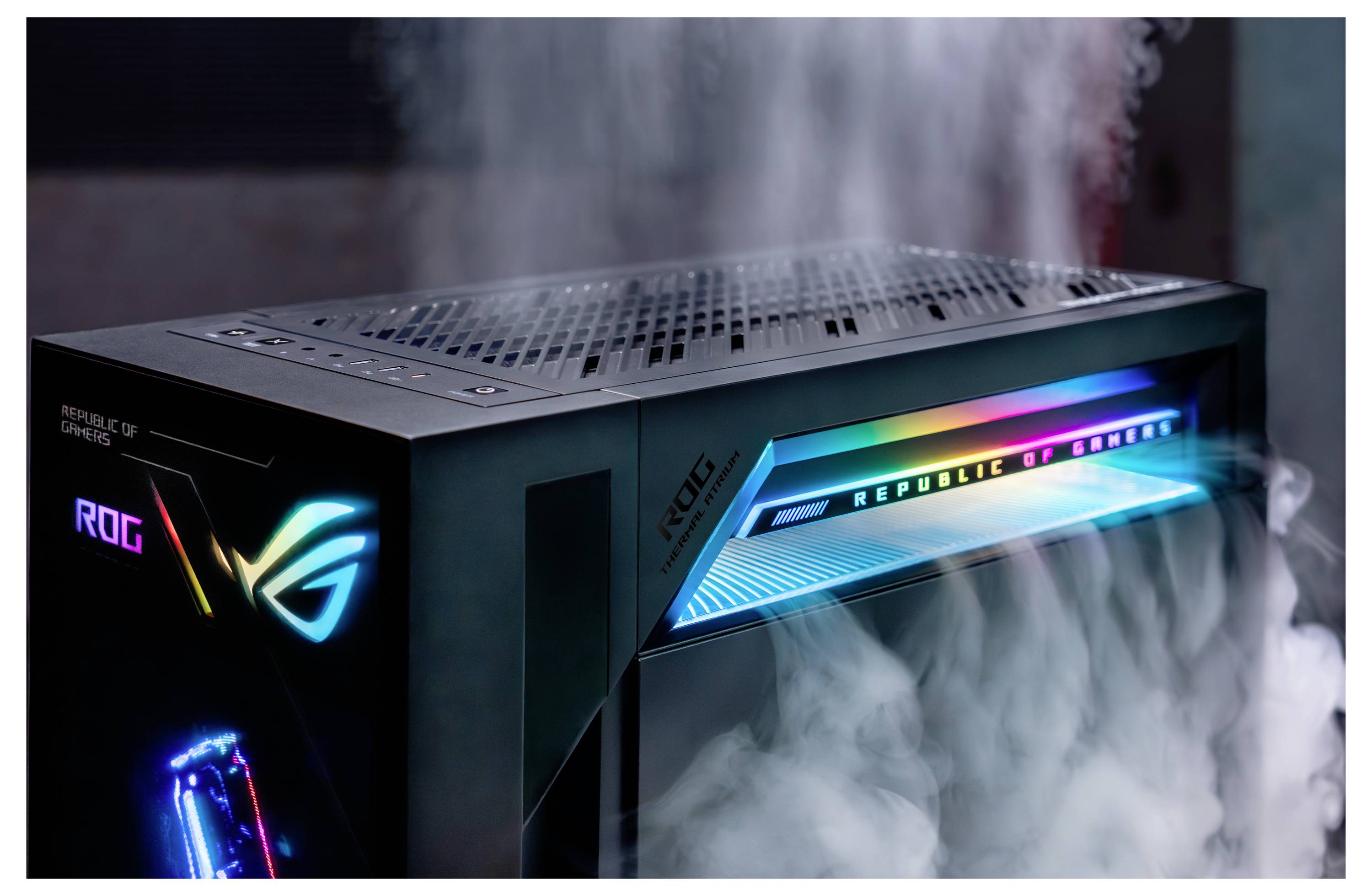 RGB osvětlená herní počítačová věž ASUS ROG s zářícím logem a předním světelným pruhem, zobrazena v kouřnatém tmavém prostředí.