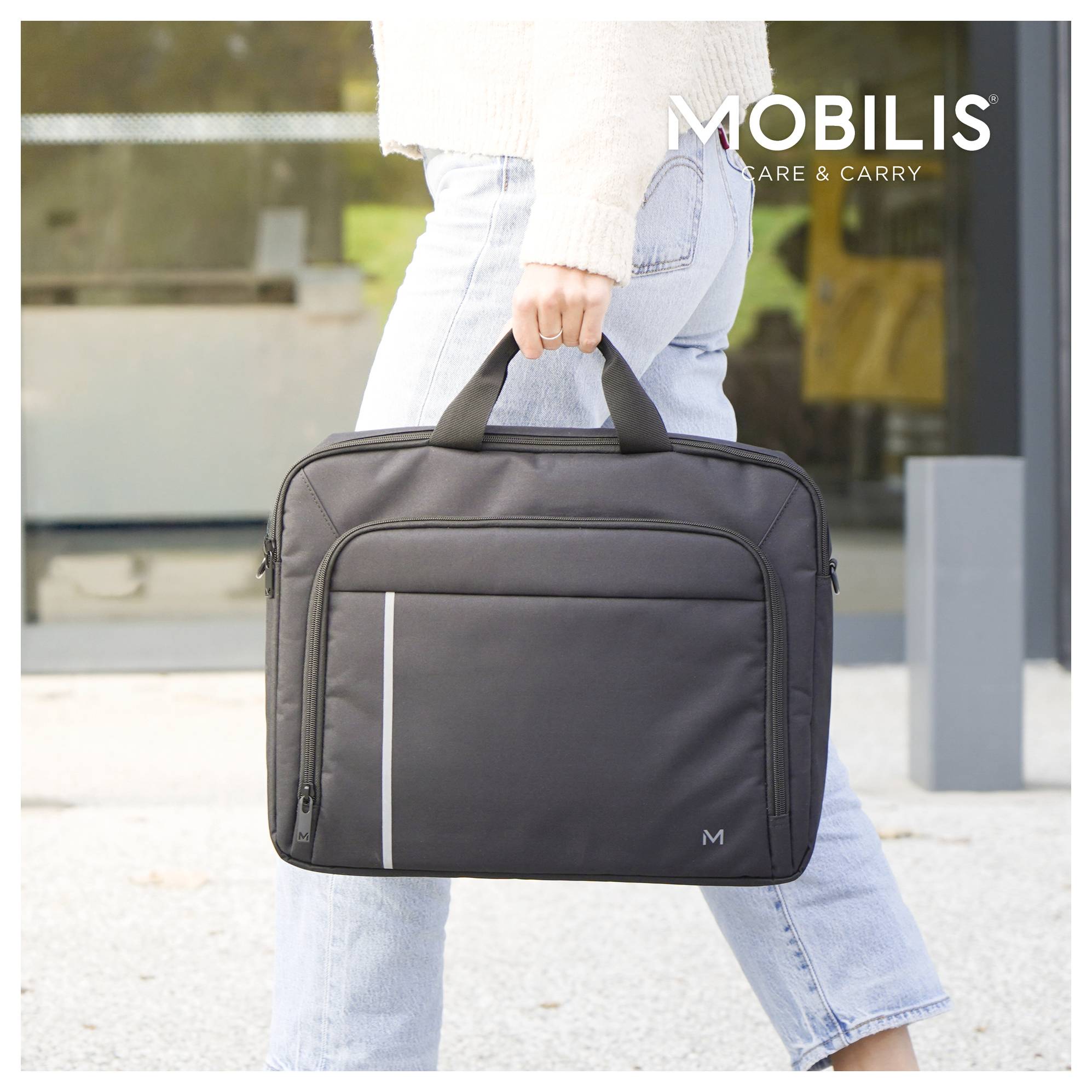 Osoba nošející černou taška na notebook MOBILIS s rukojetí venku; text značky 'MOBILIS' a 'CARE & CARRY' se objevuje v pravém horním rohu.