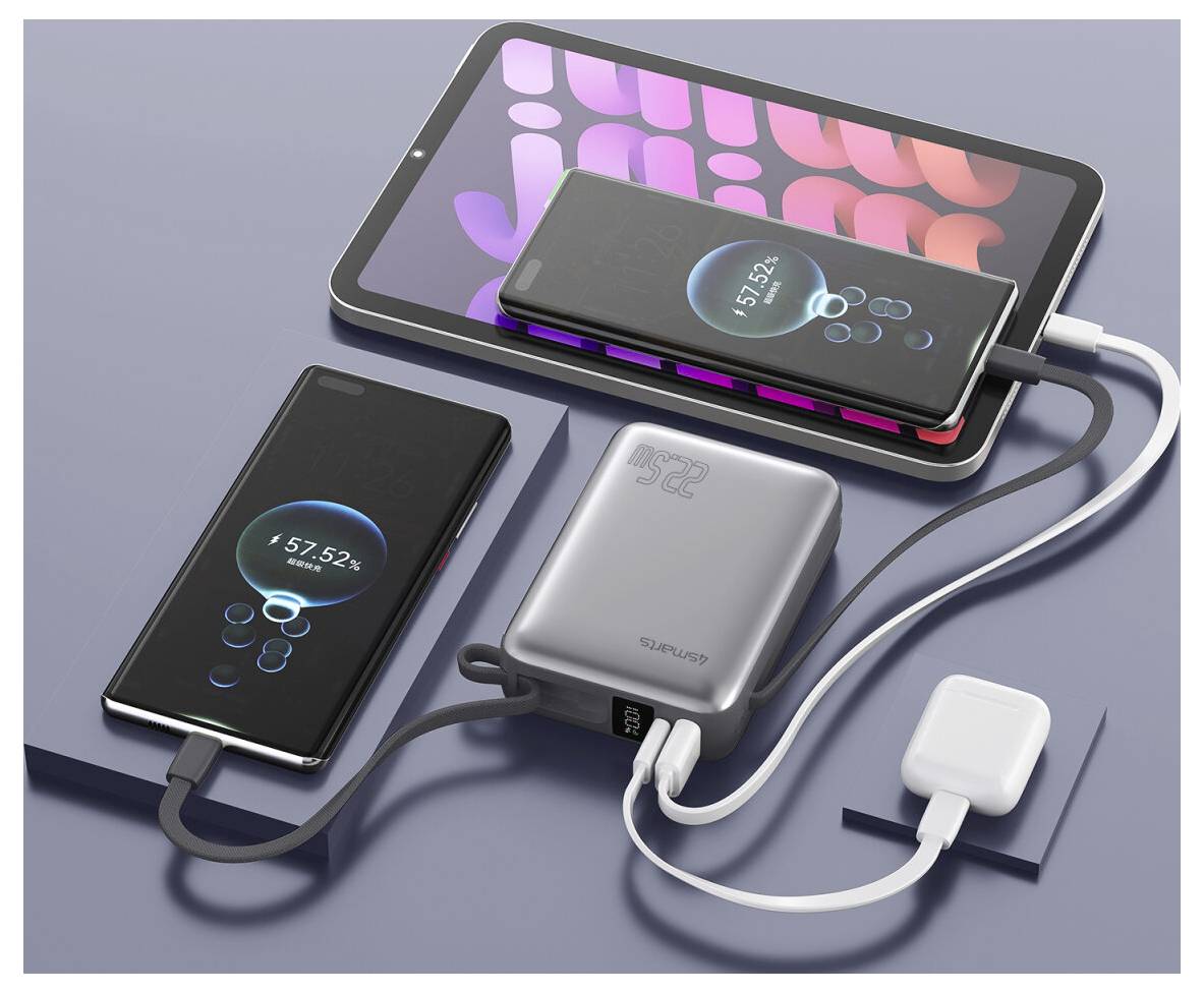 Několik smartphonů a tablet se nabíjejí z powerblanky, s kabely připojenými k nástěnné adaptéru na šedém povrchu.
