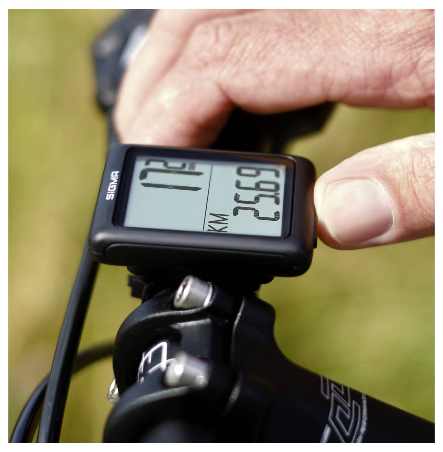 Detailní pohled na počítač GPS na řídítku jízdního kola zobrazující data jízdy, včetně rychlosti a vzdálenosti, zatímco ruka zařízení nastavuje.