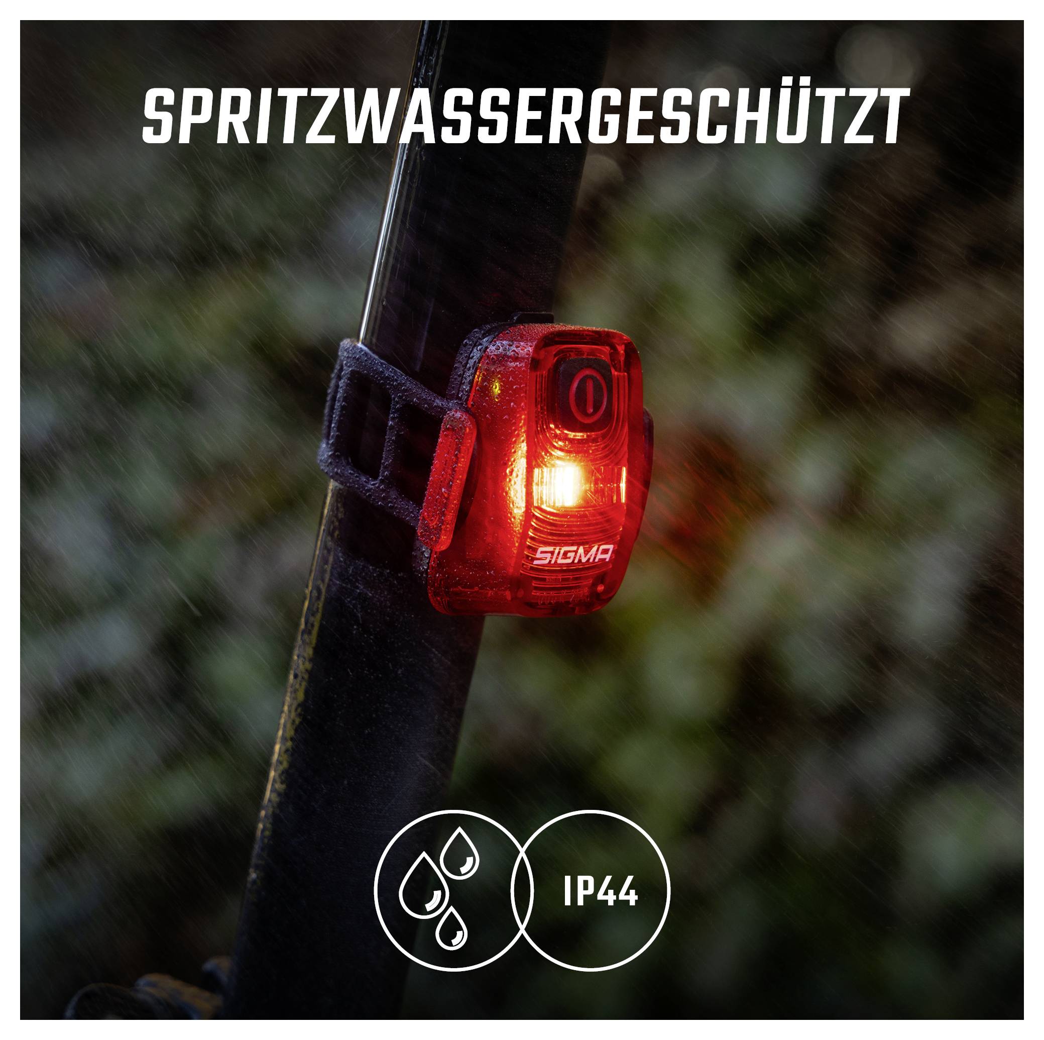 Červená zadní cyklistická lampa na sedlovce svítí v dešti; text „CHRÁNĚNO PROTI STŘÍKAJÍCÍ VODĚ" a symbol „IP44" označují ochranu proti stříkající vodě.