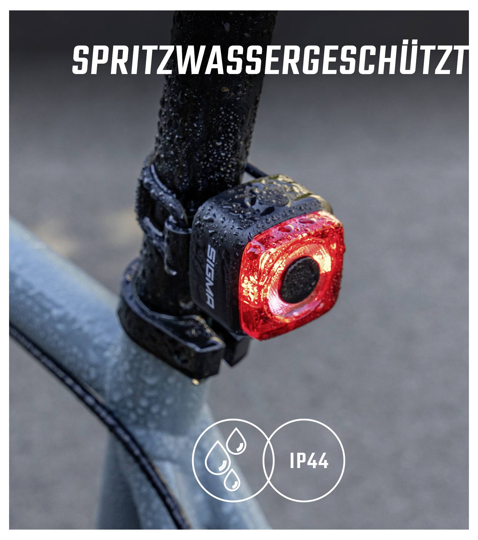 Detailní snímek červeného cyklistického zadního světla s kapkami vody; text 'CHRÁNĚNO PŘED STŘÍKAJÍCÍ VODOU' a symbol 'IP44' ukazují odolnost proti povětrnostním vlivům.