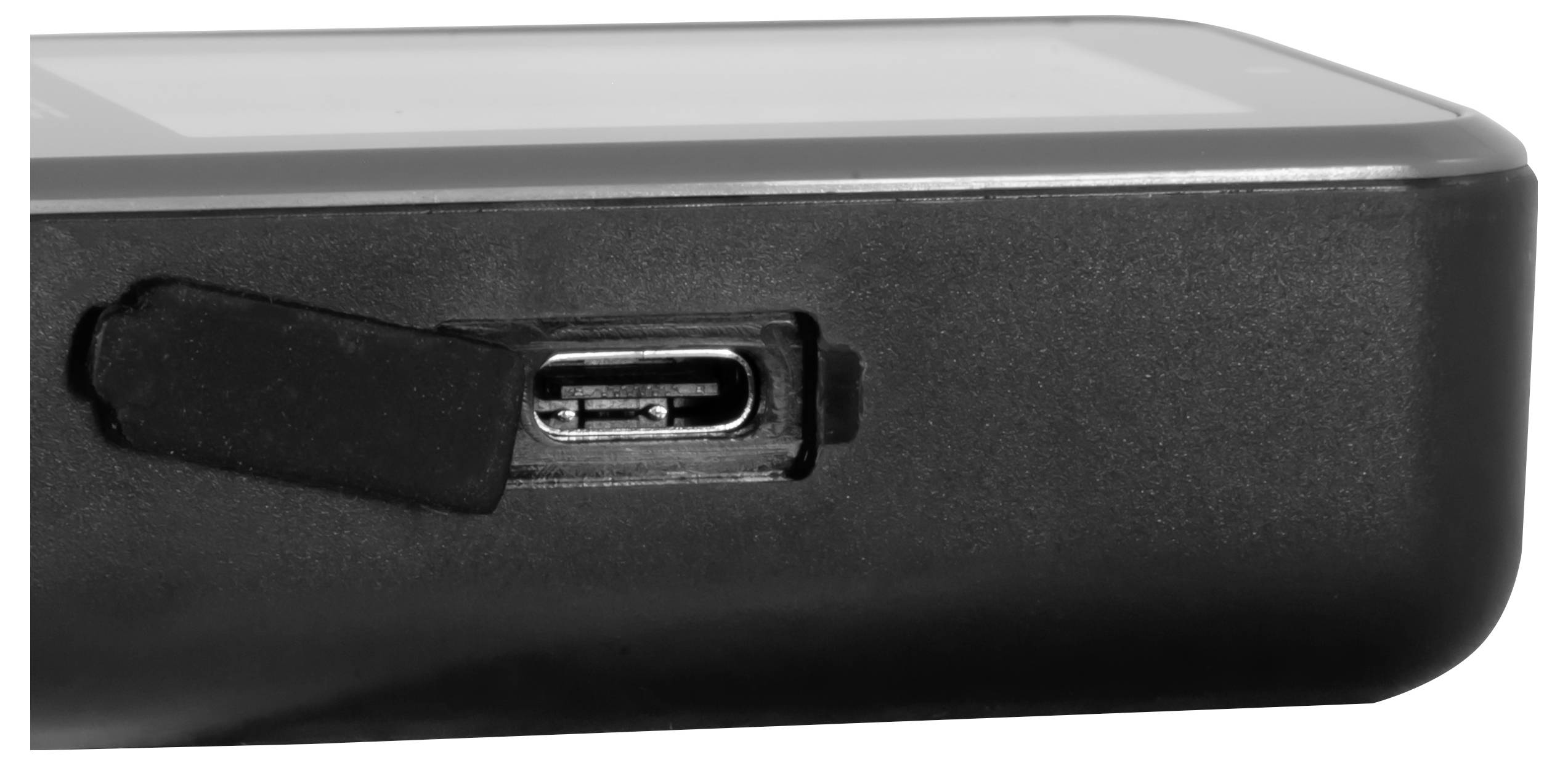 Detailní pohled na roh černého elektronického zařízení ukazující zakrytý port USB-C pro nabíjení.