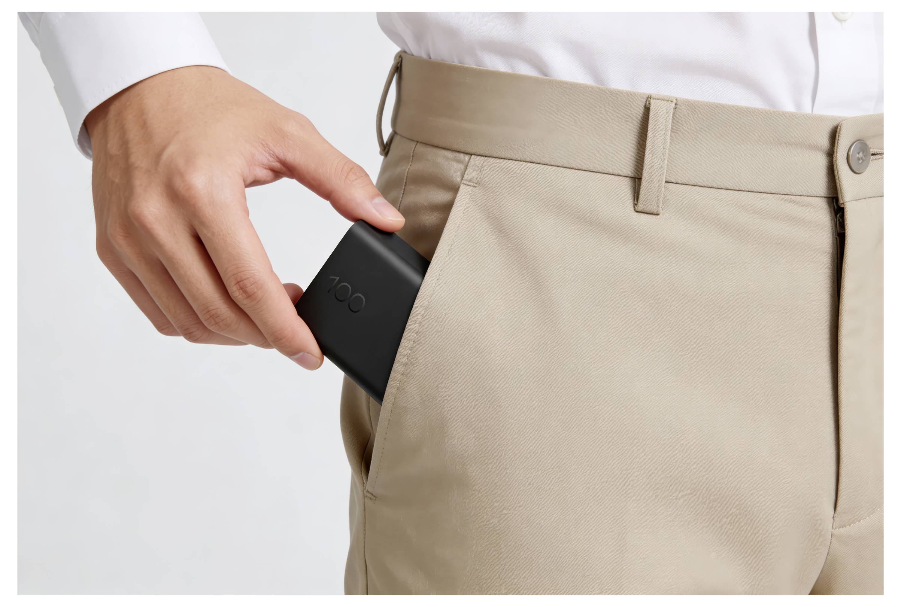 Osoba vkládající černý smartphone do bežové kalhoty kapsy.