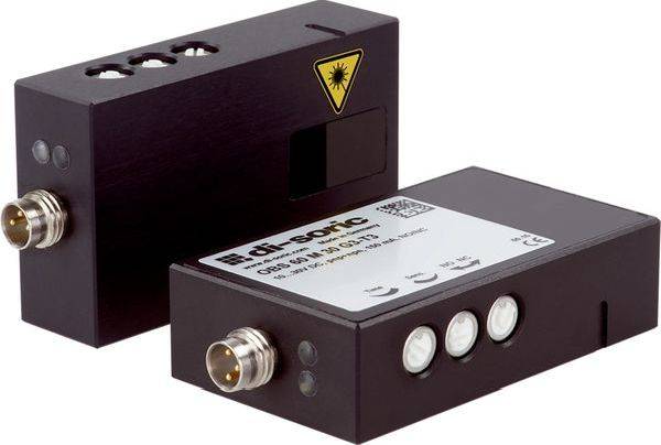 Dva černé průmyslové senzorické moduly s kovovými konektory, z nichž jeden je označen žlutým symbolem laserového varování a druhý má tři bílá kulatá tlačítka nebo indikátory.