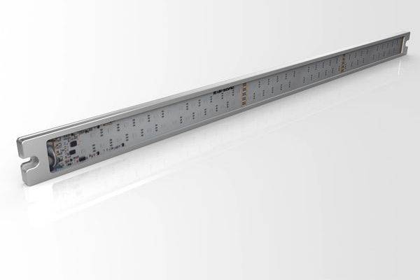 Dlouhý kovový elektronický modul nebo sestava desky plošných spojů s řadami součástek uvnitř štíhlého obdélníkového pouzdra, zobrazené na bílém pozadí.