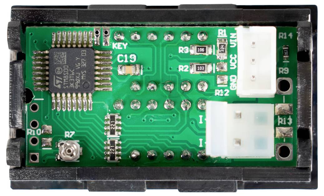 Detailní záběr elektronického obvodu uvnitř černého plastového pouzdra, ukazující mikročip, rezistory, pájené body a dva bílé konektory.