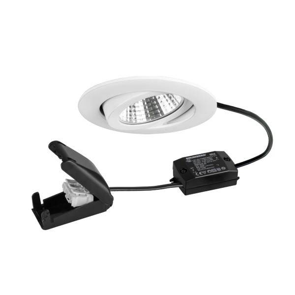 Bílé zapuštěné LED světlo se připojeným černým ovladačem a upevňovací hardware na pružinový klip na bílém pozadí.
