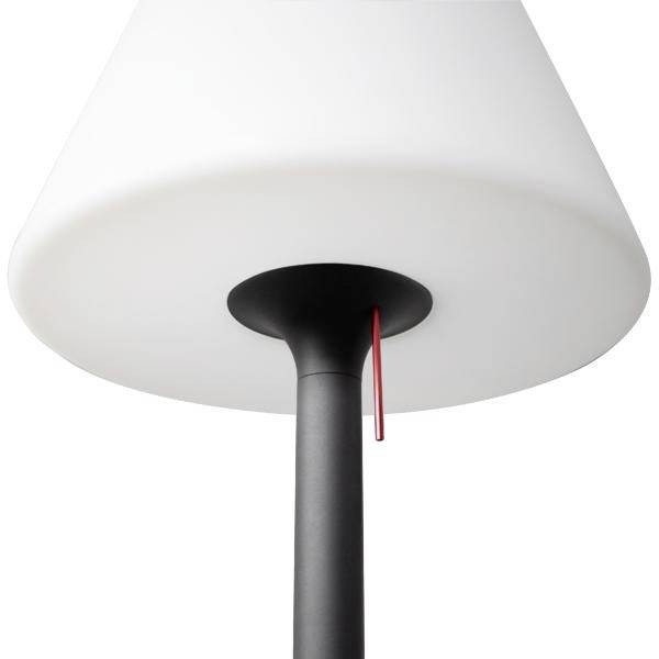 Detailní pohled na moderní stolní lampu s bílým kuželovitým stínítkem, černou stopkou a červeným tahovým řetězem na bílém pozadí.