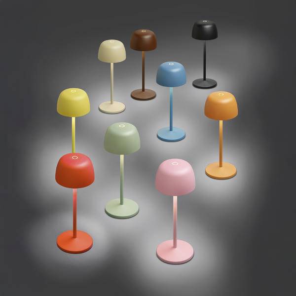 Osm barevných lamp ve tvaru hub na štíhlých noženích uspořádaných na tmavě šedé podlaze, každá vrhá měkké bodové světlo.