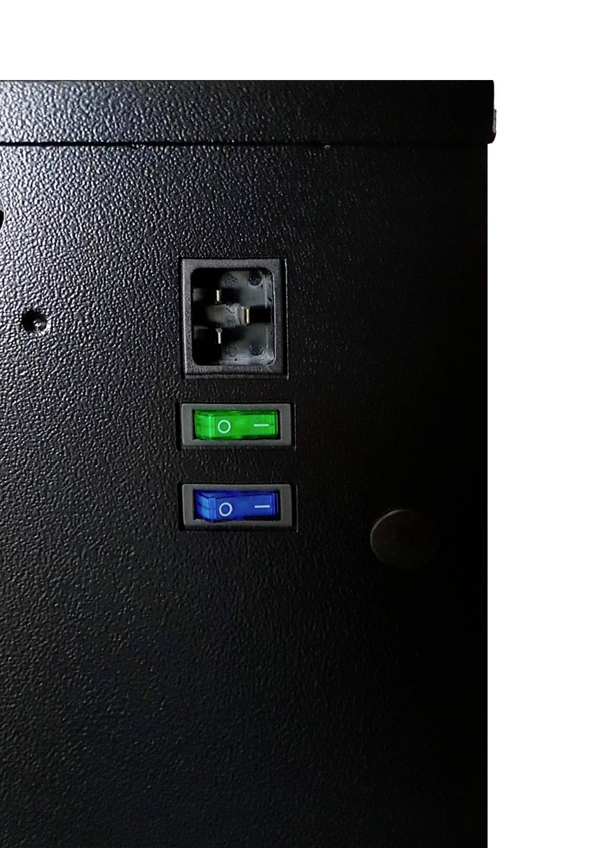 Zvětšený snímek černého panelu elektronického zařízení s napájecí zásuvkou a dvěma pákovými spínači, jedním zeleným a jedním modrým, určenými pro kontrolu napájení.