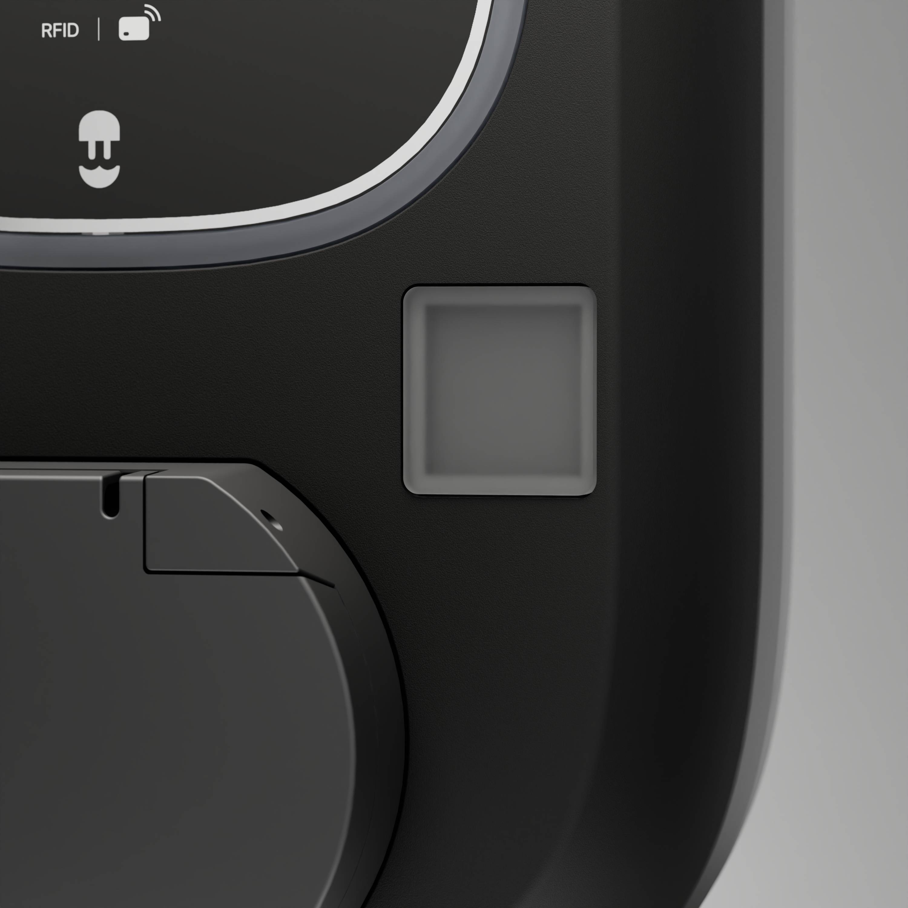 Detailní snímek černého zařízení s podporou RFID se čtvercovým senzorem nebo tlačítkem a částečně viditelným zakrytým oddílem.