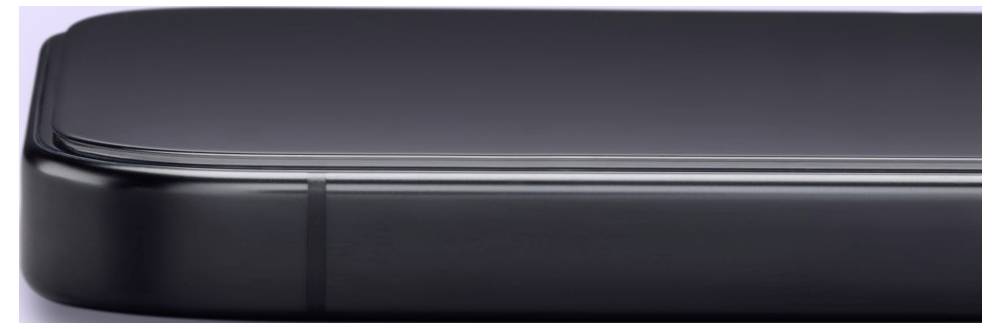 Detailní záběr na zaoblený roh černého smartphonu a lesklou hranu na světlém pozadí.