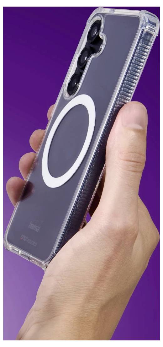 Ruka držící smartphone v průhledném pouzdře s velkým bílým kroužkem ve stylu MagSafe, zobrazeno na fialovém pozadí.