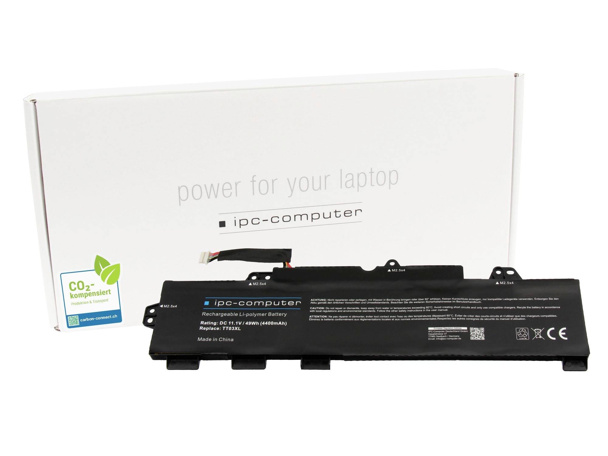 Černý náhradní akumulátor do notebooku před bílou krabicí s nápisem „power for your laptop" a „ipc-computer", se samolepkou na kompenzaci CO2.