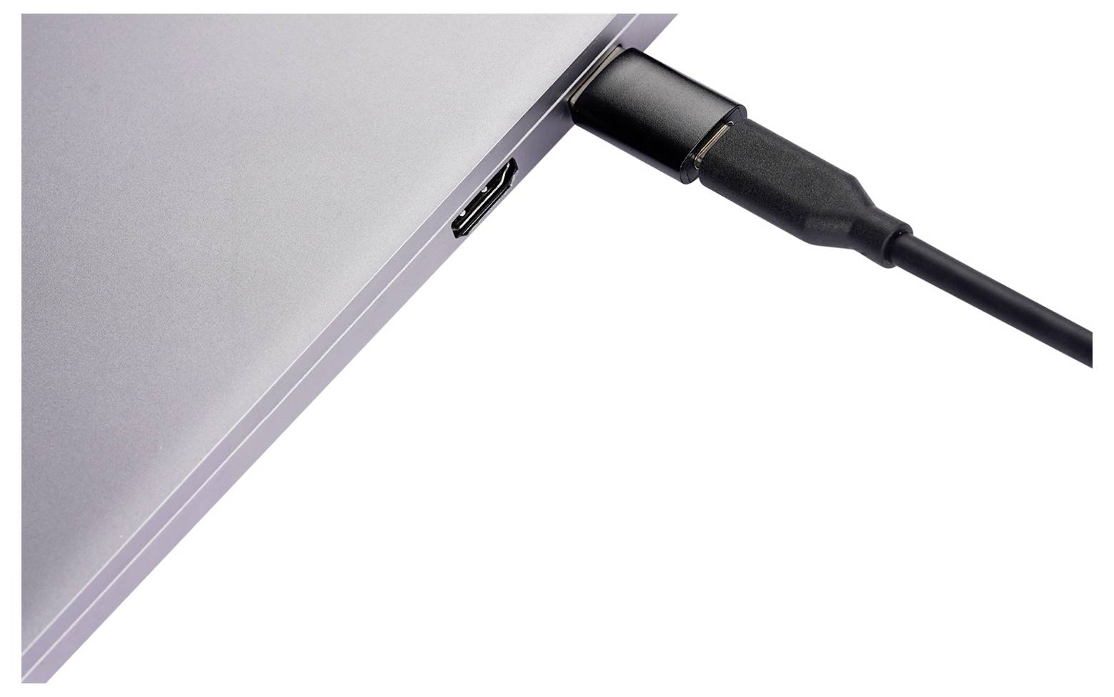 Detailní snímek černého kabelu USB-C zapojeného do strany stříbrného notebooku.