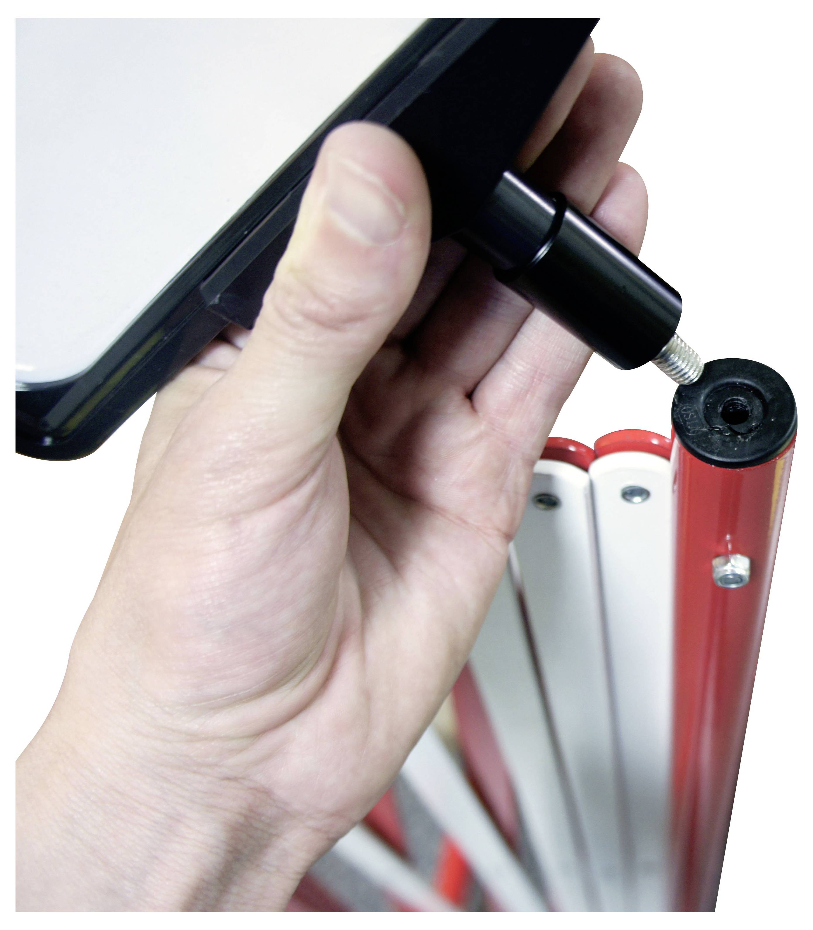 Ruka používající černý stylus na dotykové zařízení poblíž červených a bílých hřbetů pořadačů.
