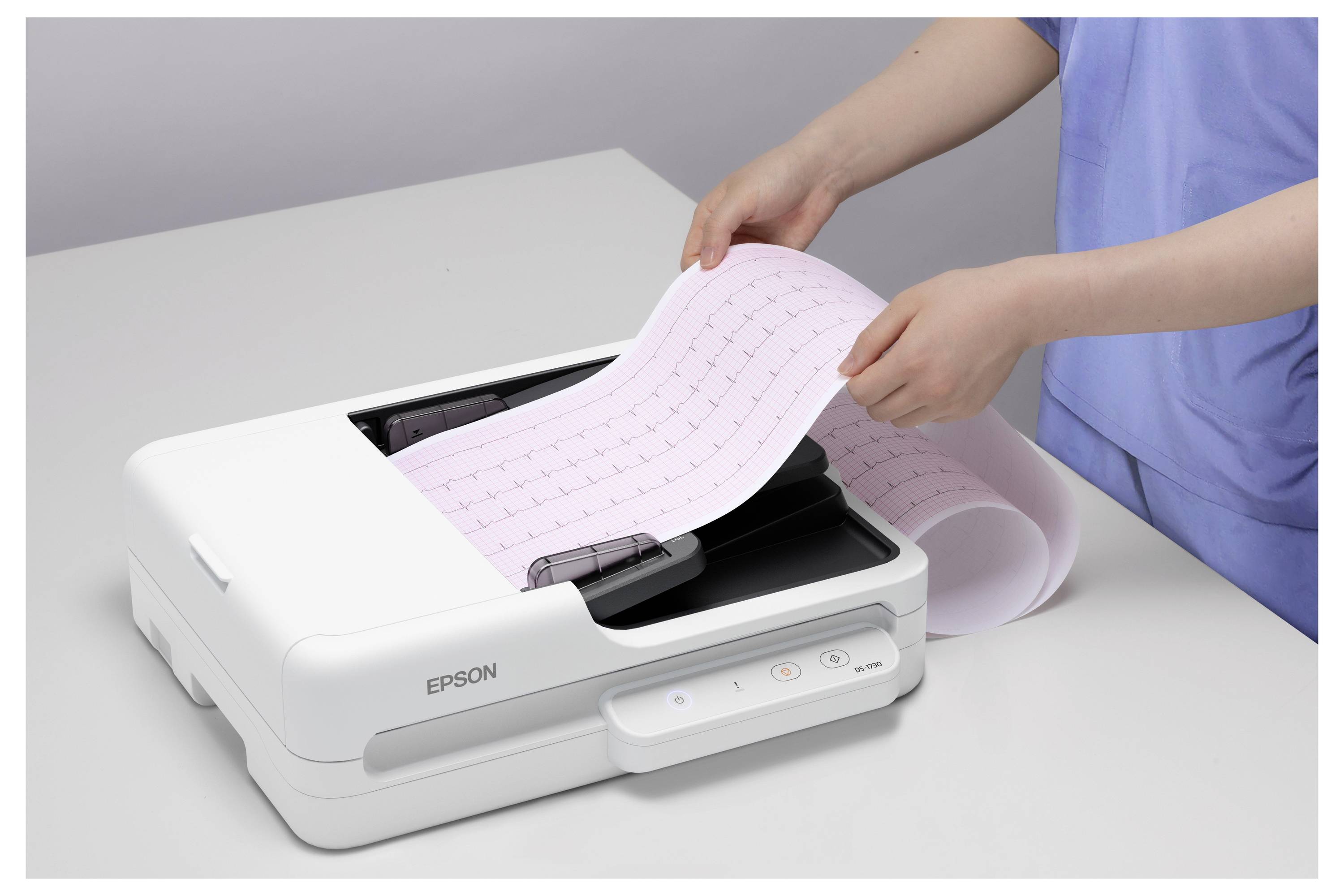 Osoba vkládá dlouhý pás růžového papíru do tiskárny Epson na stole.