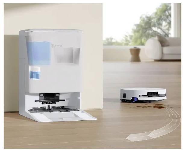 Robot vysavač čistí rozlitou tekutinu na dřevěné podlaze vedle samovyprazdňující se doknovací stanice v jasné obývacím pokoji.