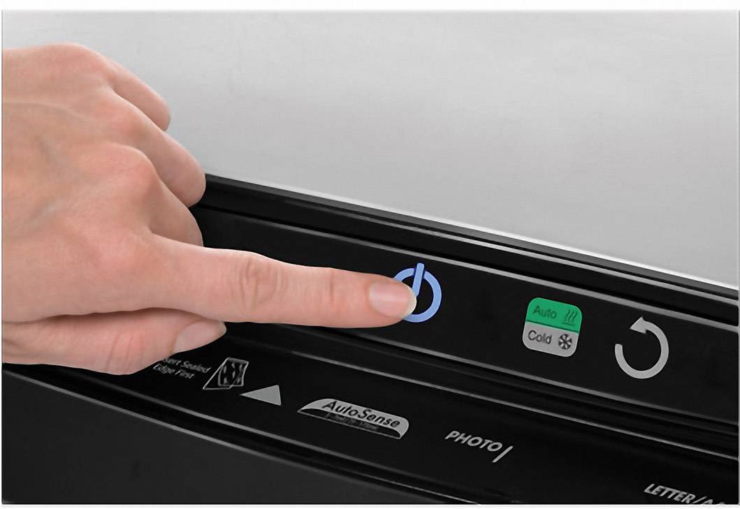 Jedna ruka tiskne tlačítko zapnutí na zařízení s dalšími tlačítky pro 'Auto', 'Cold' a symbol kruhové šipky.