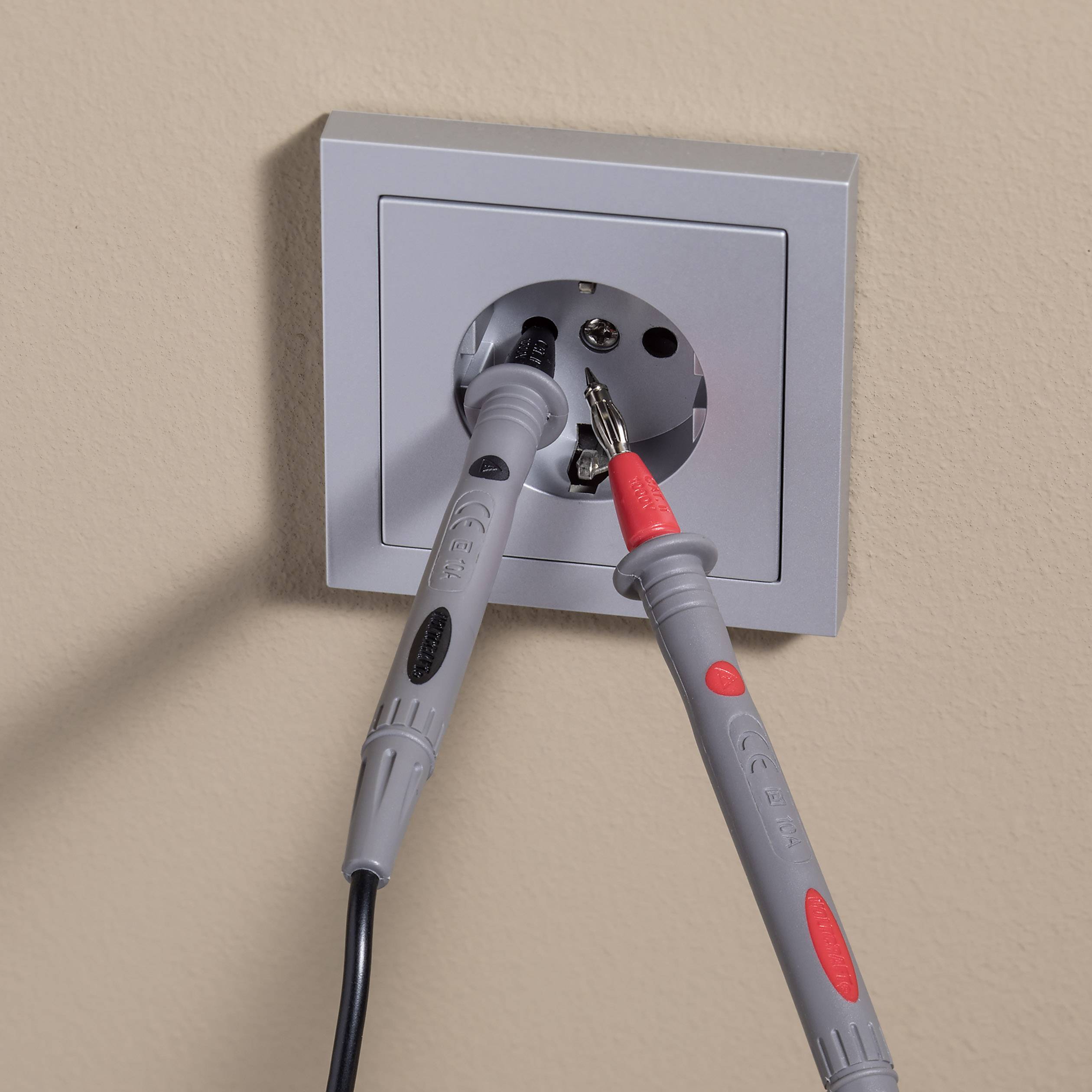 Elektrická zásuvka se dvěma testovacími hroty, které jsou zavedeny do kontaktů pro provedení elektrických měření.