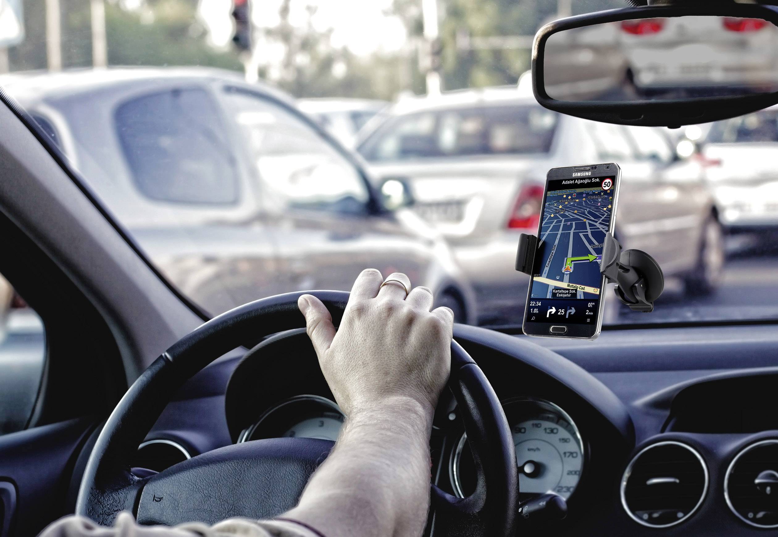 Řidič automobilu naviguje hustým provozem pomocí smartphonu upevněného v držáku, který slouží jako GPS navigace.