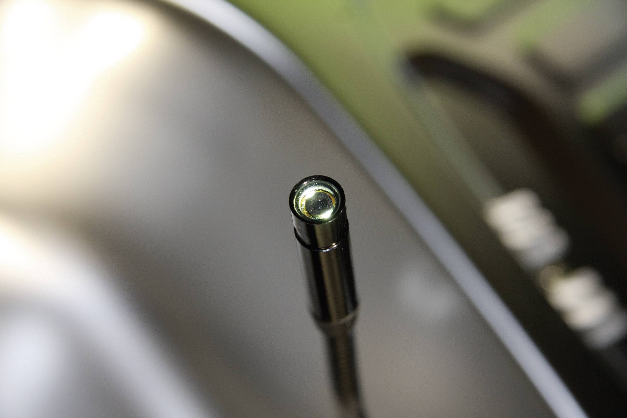 Detailní záběr mikrofonu se zaostřeným pohledem na špičku kapsle, obklopený rozostřeným pozadím.