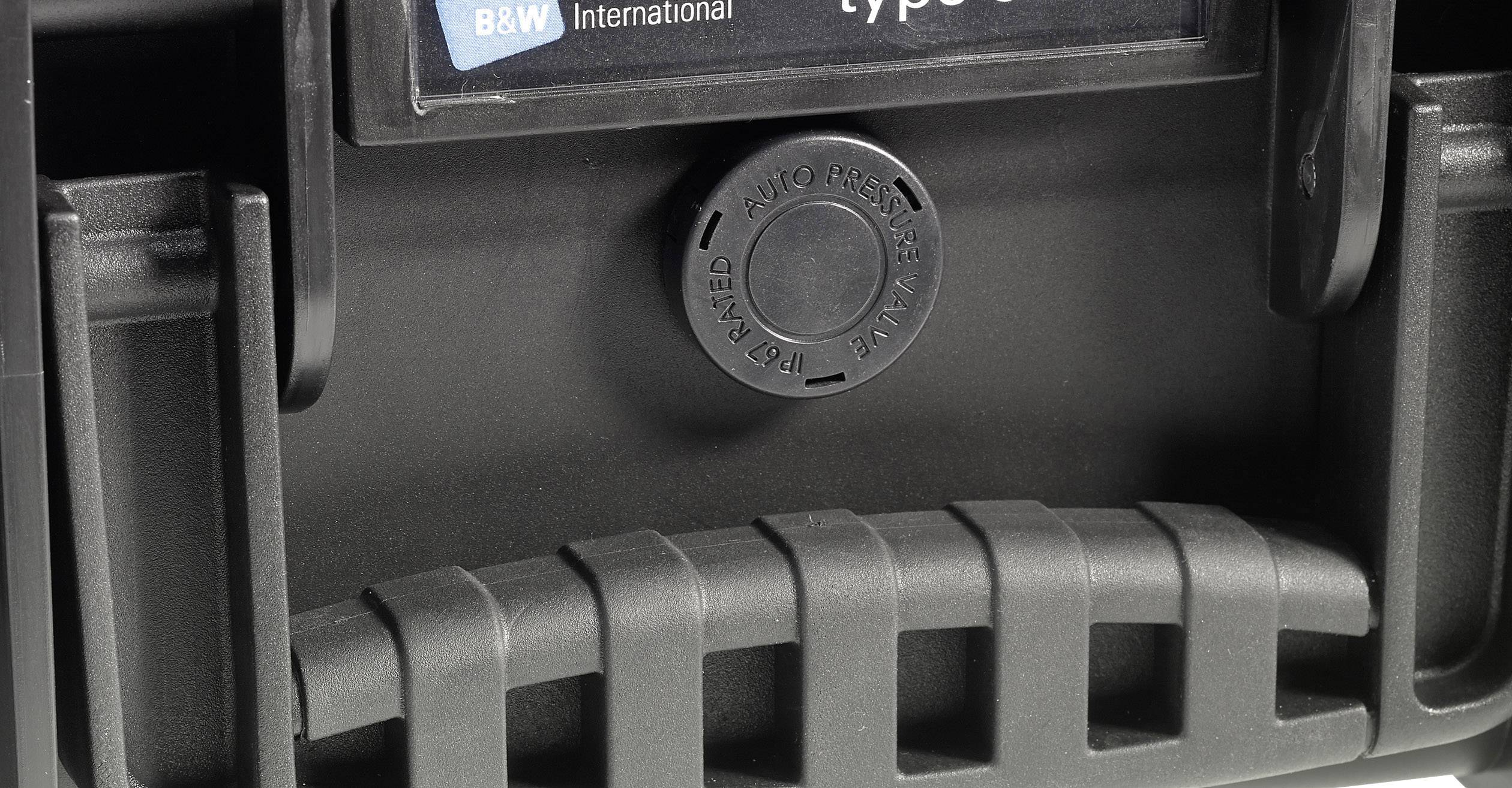Detailní záběr černé plastové krabičky s kulatým tlačítkem uprostřed, označené nápisem ,auto air valve'.
