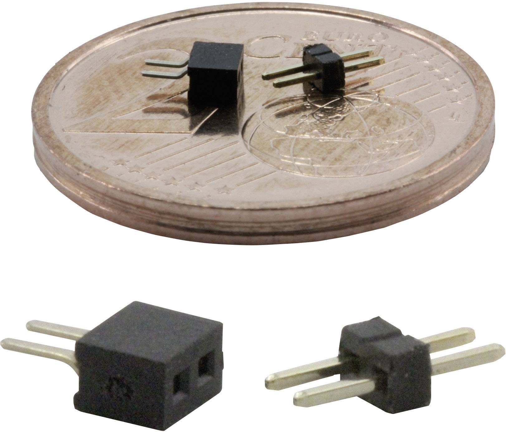 Malý černý elektronický čip se dvěma kovovými kolíky leží na měděné minci; vedle jsou další čipy.