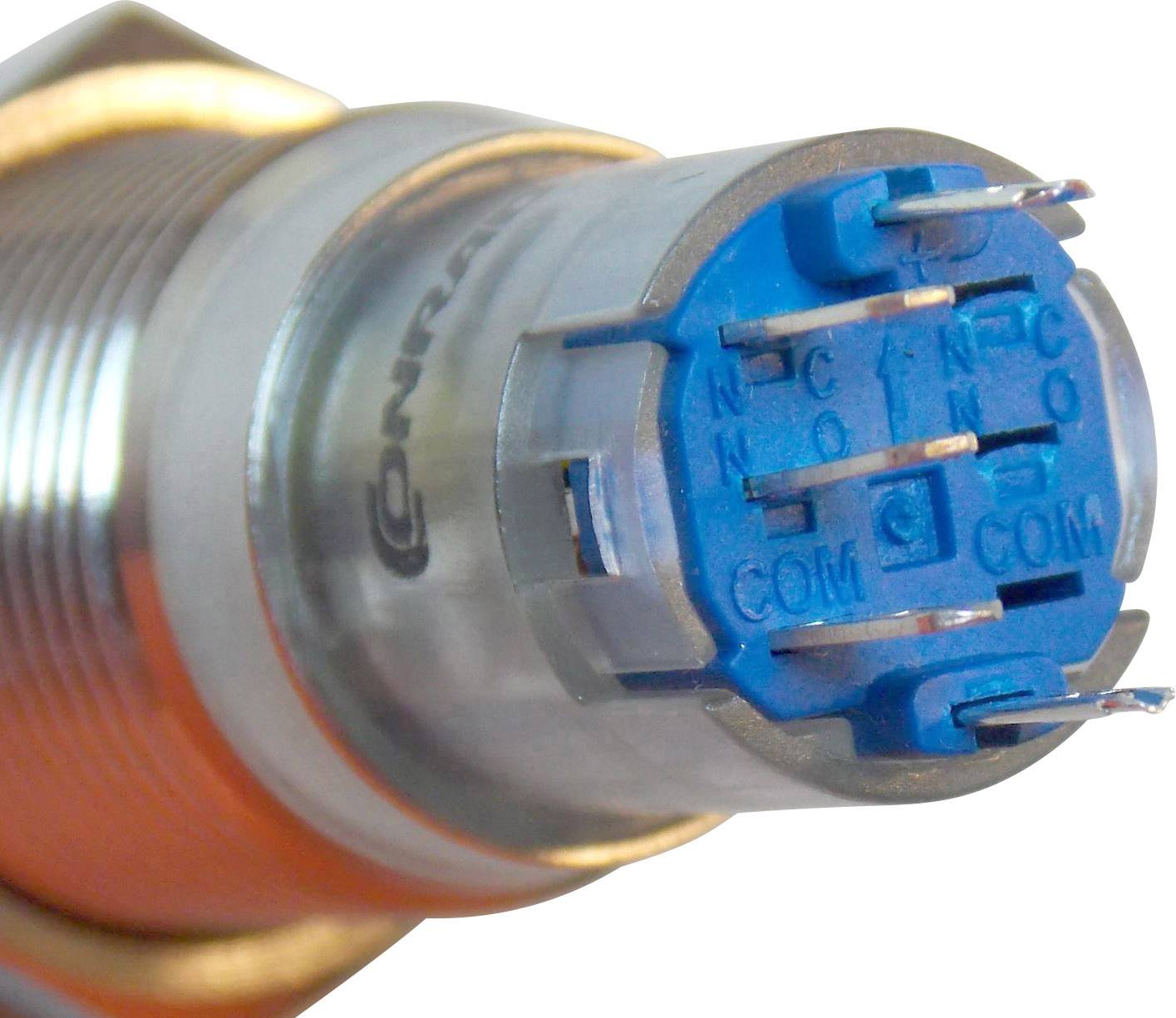 Detailní záběr modrého elektrického konektoru s několika připojovacími kolíky, obklopeného kovovým pouzdrem.