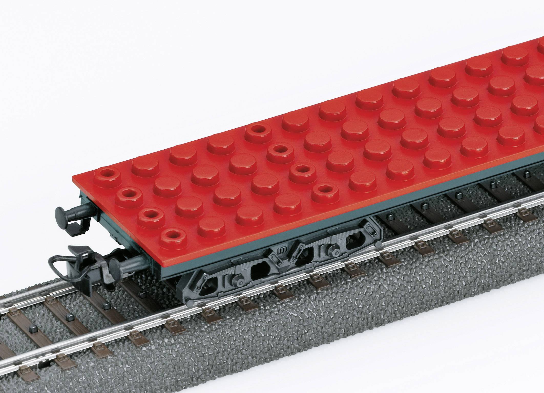 Červený nákladní vagón LEGO na kolejovém úseku; detailně zpracovaný hračkářský model.