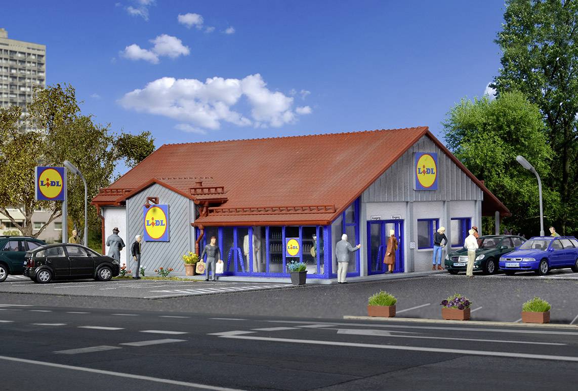 Supermarket Lidl s červenou střechou, obklopený parkujícími auty. Několik lidí vstupuje a opouští obchod.